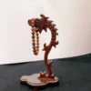 Carved wooden dragon holding prayer beads sculpture.