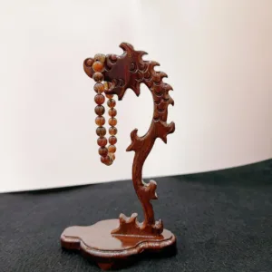 Carved wooden dragon holding prayer beads sculpture.