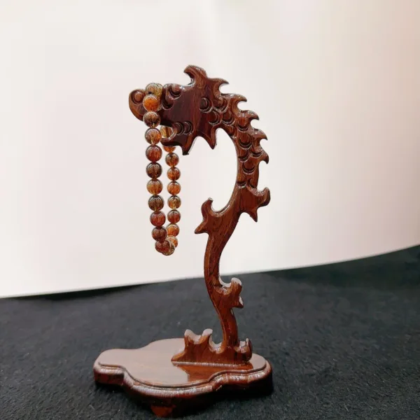 Carved wooden dragon holding prayer beads sculpture.