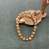 Wooden hand sculpture holding beaded bracelet.