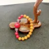 Wooden bracelet display stand with colorful beaded jewelry.