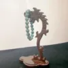 Carved wooden stand holding jade bracelet.