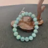 Blue beaded bracelet on wooden display stand.