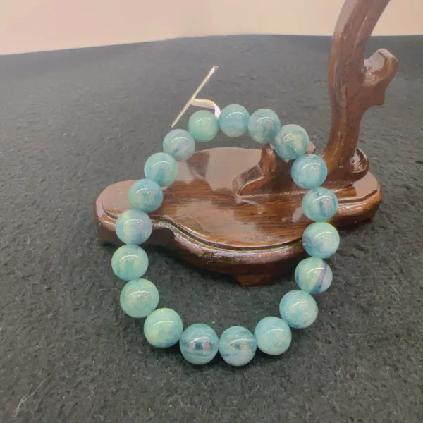 Blue beaded bracelet on wooden display stand.