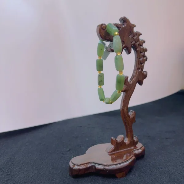 Jade bracelet displayed on wooden stand.