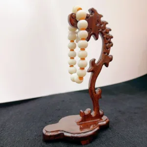 Carved wooden stand displaying beaded necklace.