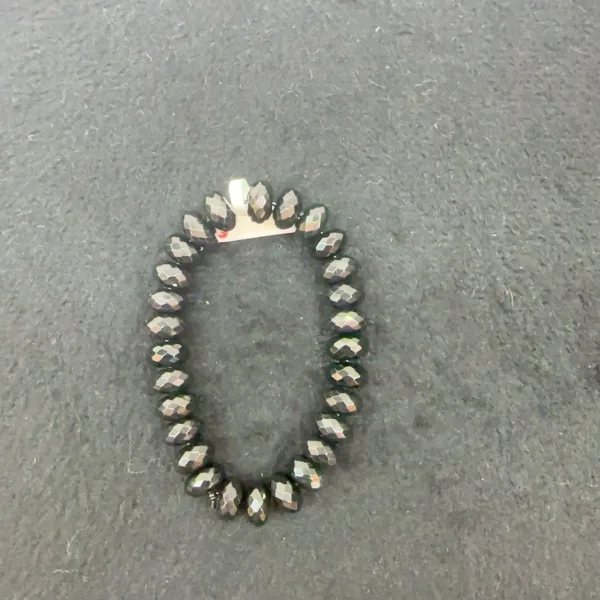 Black beaded bracelet on gray background.