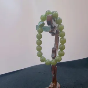 Green bead bracelet on wooden stand.
