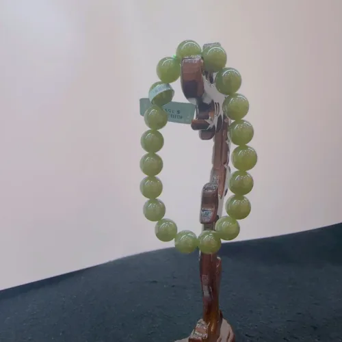 Green bead bracelet on wooden stand.