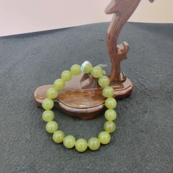 Green bead bracelet on wooden display stand.