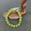 Green bead bracelet on wooden palette display.