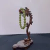 Green beaded bracelet on wooden display stand.