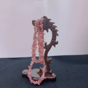 Carved wooden stand displaying pink quartz necklace.