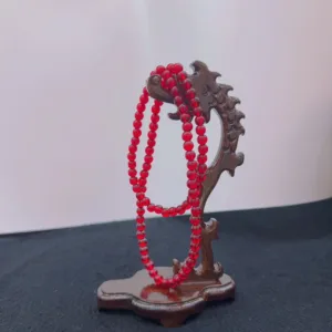 Red beaded necklace on wooden display stand.