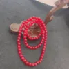 Red beaded necklace on dark surface.