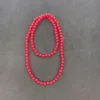 Red beaded necklace on gray background.