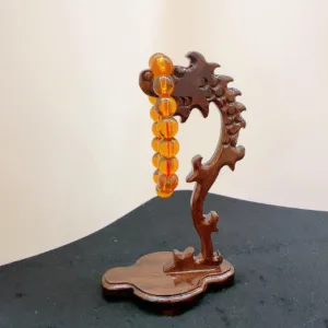 Wooden dragon sculpture holding amber beads.