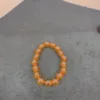 Orange beaded bracelet on grey background.