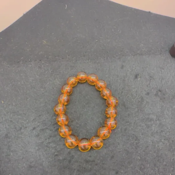 Orange beaded bracelet on grey background.