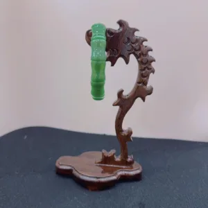 Carved wooden stand with green glass object.