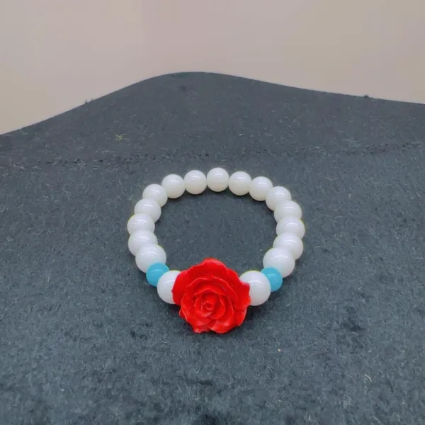 White beaded bracelet with red rose charm.