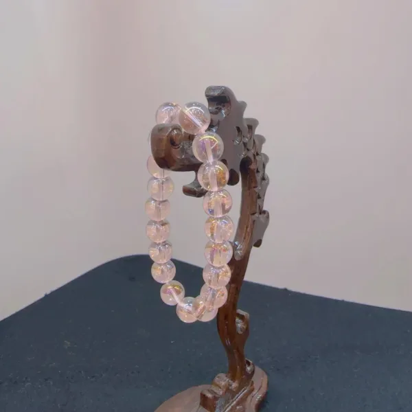 Wooden jewelry stand holding a clear beaded necklace.