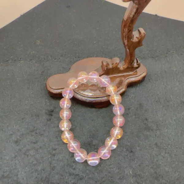 Iridescent bracelet on wooden stand against gray background.