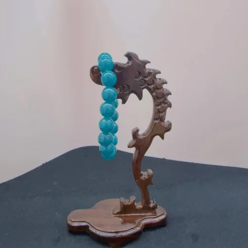 Blue beads on carved wooden stand.