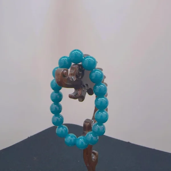 Turquoise beaded bracelet on wooden stand.