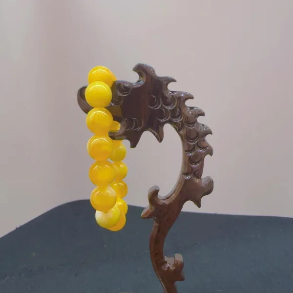 Yellow beaded bracelet on carved wooden stand.