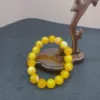 Yellow beaded bracelet on wooden display stand.