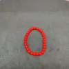 Red beaded bracelet on gray background