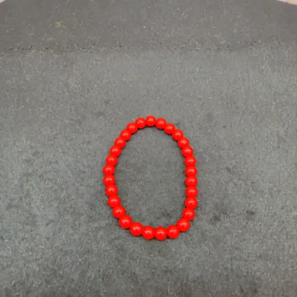 Red beaded bracelet on gray background