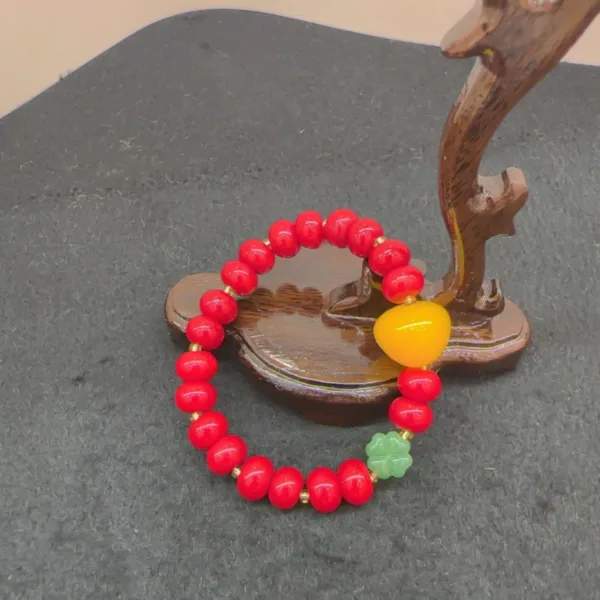 Red beaded bracelet with yellow accent on stand.