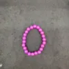 Purple beaded bracelet on a gray surface.