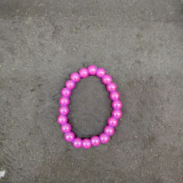 Purple beaded bracelet on a gray surface.