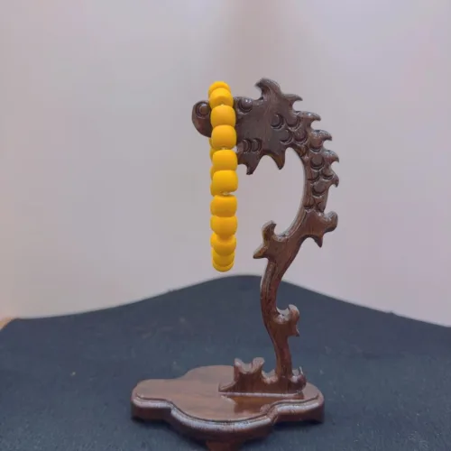 Wooden dragon sculpture with yellow beads on tail.