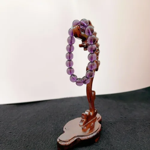 Purple beaded bracelet on wooden display stand.