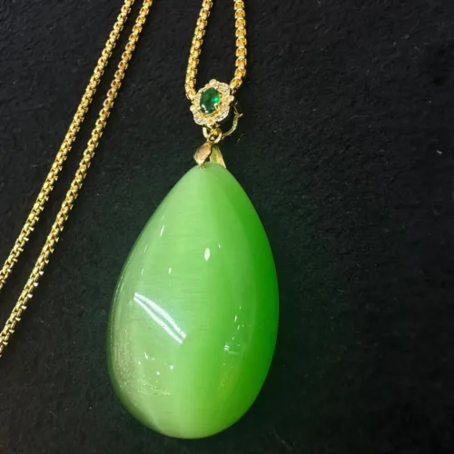 Green jade pendant with gold chain and emerald detail.
