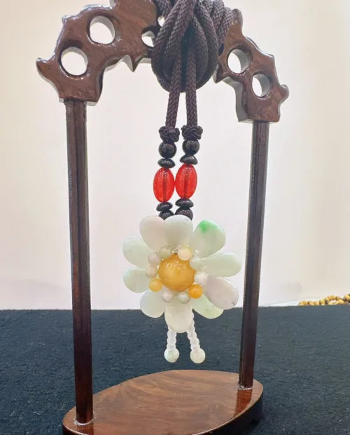 Jade flower ornament on wooden stand.