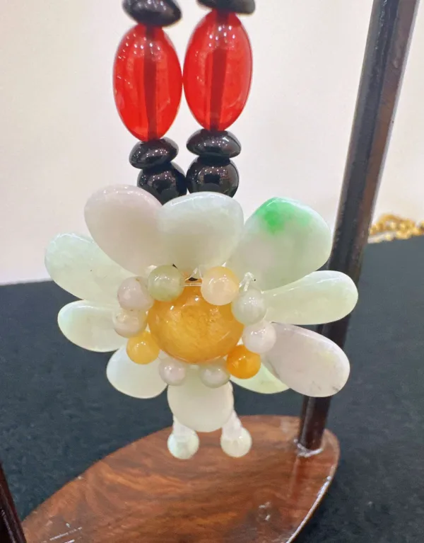 Handcrafted flower-shaped jade necklace on display stand.