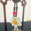 Jade flower pendant on wooden stand.