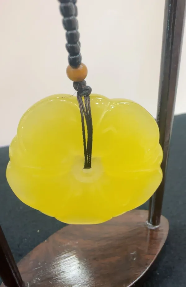 Yellow carved flower pendant on bead necklace.