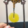 Beaded necklace with yellow jade pendant on wooden stand.