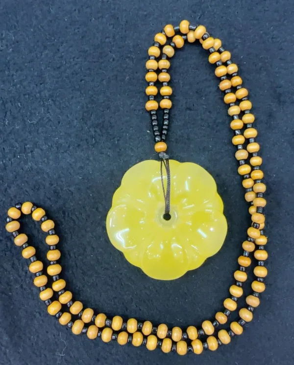 Yellow beaded necklace with flower pendant.