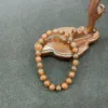 Wooden leaf tray with beaded bracelet on table.