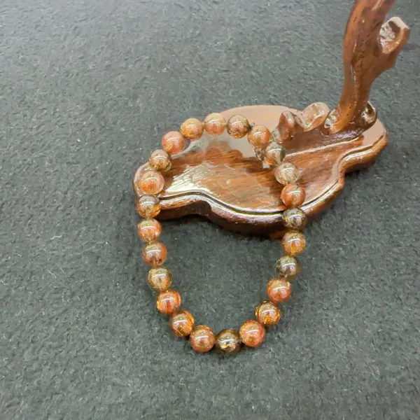 Wooden leaf tray with beaded bracelet on table.