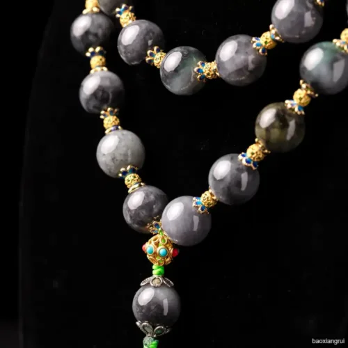 Elegant gray beaded necklace with gold accents on black.