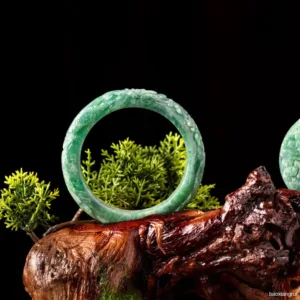 Jade bracelet on wood with green plant background.