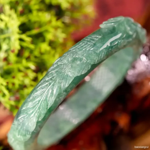 Carved jade bangle close-up with blurred green background.